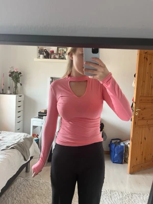 Rosa långärmad topp med cut out - Rosa långärmad topp med unik cut out-u-ringning vid halsen. Toppens passform är tight och den har en mjuk, stretchig känsla.