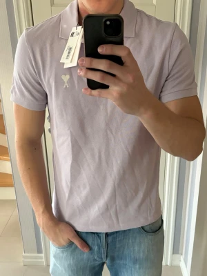 Ljuslila pikétröja från Ami - Denna galet snygga populära lila Ami Paris piken i storlek M säljes. Helt ny tagen är kvar och han på bilden är 187 cm och väger 85 kg. Grym passform och perfekt nu till sommaren! Nypris på flera tusen så riktigt kap. Tveka inte vid minsta fråga eller fundering!
