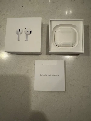 Apple AirPods 4 - Säljer ett par vita Apple AirPods 4 med trådlöst laddningsetui. Snygg och stilren design i plast, perfekt för dig som vill ha grymt ljud och smidig anslutning till din iPhone eller annan Apple-enhet. Kommer i originalförpackning med tillbehör. Kom med när vi köpte ny mobil. 
