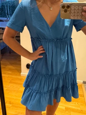 Blå volangklänning med v-ringning - Supersöt blå kortklänning med v-ringning och volanger. Säljer då den inte kommer till användning😊Pris kan diskuteras 