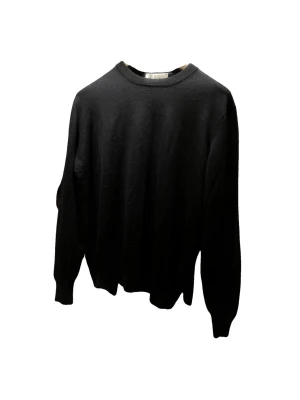 Brunello Cucinelli - Klassisk svart stickad tröja från Brunello Cucinelli med rund halsringning och långa ärmar. Tröjan har en enkel och stilren design, perfekt för dig som gillar tidlösa plagg. Materialet känns mjukt och exklusivt.