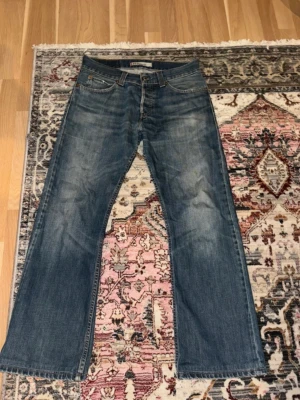 Levi's blå bootcut jeans - Säljer ett par klassiska blå bootcut jeans från Levi's med snyggt slitna detaljer och fem fickor. Jeansen har normal midja och raka ben med lätt utsvängning nertill. Perfekta för en avslappnad och trendig look.