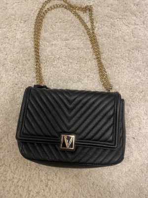 Svart Victoria Secret väska med guldkedja - Väskan är i bra skick men den har tappat lite läderfärg på kanterna annars superfin o i bra skick 