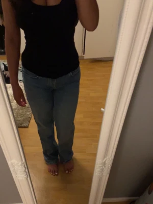 Blå raka jeans  - Säljer ett par blå jeans med rak passform och låg midja. Jeansen har klassisk femficksdesign och stängs med dragkedja och knapp. 