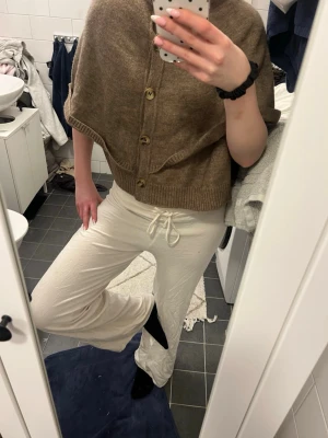 Vita mjukisbyxor - Säljer ett par vita mjukisbyxor med bred resår och dragsko i midjan. Byxorna har raka ben och är tillverkade i ett mjukt och bekvämt material, perfekta för en avslappnad stil. Passar dig som gillar en clean och enkel look.