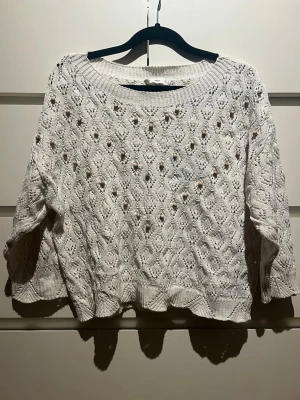Vit virkad stickad tröja - Säljer en väldigt snygg vit stickad tröja med virkat hålmönster och bred rund halsringning. Tröjan har trekvartsärmar och ribbade muddar vid ärmslut och nederkant. Perfekt för lager på lager och ger en chill vibe till din outfit. Funkar både när de är lite kallare ute men också på sommaren❣️