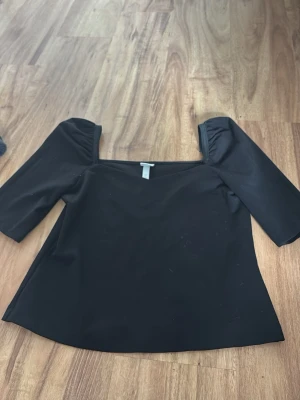 Svart offshoulder topp från H&M - Snygg svart offshoulder topp från H&M med trekvartsärm. Toppen har en stilren och enkel design som passar perfekt till jeans eller kjol. Materialet känns mjukt och stretchigt, vilket gör den bekväm att bära. Perfekt för dig som gillar trendiga och minimalistiska plagg.