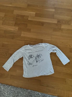 Vit pyjamaströja med hundmotiv - Mysig vit långärmad pyjamaströja med tryck av två hundar och texten 'Best Friends Forever' på framsidan. Tröjan har rund hals och är tillverkad i mjukt material, perfekt för slappa kvällar hemma.