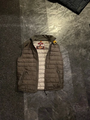Olivgrön dunväst från Parajumpers - Olivgrön dunväst från Parajumpers , köpt på plick, med quiltad design och två dragkedjefickor framtill. Västen är lätt och bra mot våren!   Den är storlek YM, vilket liknas vid en XS. Hör av er vid några funderingar! Pris kan diskuteras