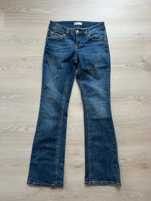 Blå bootcut jeans från gina - Snygga blå bootcut jeans från gina med klassisk femficksdesign och kontrastsömmar. Jeansen har låg midja och är tillverkade i denim med lätt tvättad look. Perfekta för en avslappnad och trendig stil.