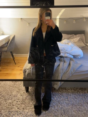 Svart kort kappa med guldknappar - Snygg mörkblå kappa med breda slag och dekorativa guldknappar framtill. Perfekt till våren inte för varm eller kall. Modellen är kort och har en boxig passform som ger en trendig look. Perfekt att styla över en crop top och jeans för en cool outfit. 