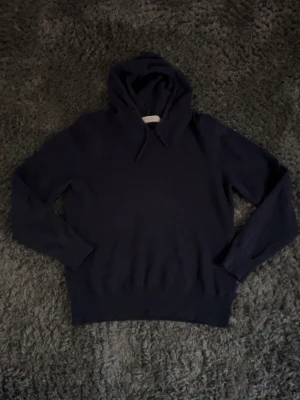 Mörkblå Kashmir tröja från Sayless - Mörkblå hoodie från Sayless i mjuk cashmereblandning. Klassisk modell med huva och dragsko, ribbade muddar vid ärmslut och nederkant. 