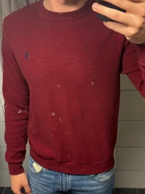 Vinröd tröja från Polo Ralph Lauren - Snygg vinröd tröja från Polo Ralph Lauren med rund halsringning och diskret blå logga broderad på bröstet. Tröjan har långa ärmar och ribbade muddar vid ärmslut och nederkant. Perfekt till jeans för en clean och stilren look.
