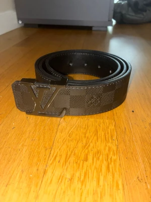 Svart schackrutigt bälte - Säljer ett svart schackrutigt bälte som är väldigt snygg att ha på sig. Den passar till många outfits. Det är lite slitet på märket där framme men det syns inte när man har på sig det.