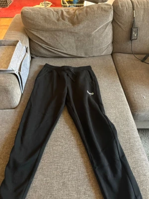 Svarta mjukisbyxor från BORG - Snygga svarta mjukisbyxor från BORG med logga på benet. Byxorna har dragsko i midjan och raka ben. Perfekta för chill eller träning. Mjukt material som känns skönt mot huden.
