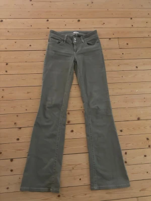 Gröna jeans från Nelly  - Snygga gröna bootcut jeans från Nelly med låg midjal. Jeansen har dekorativ söm på bakfickan och är tillverkade i ett mjukt bomullstyg. Perfekta för dig som gillar en avslappnad men trendig stil. I nyskick, använda två gånger. 