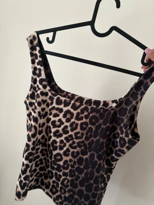 Leopardmönstrad ärmlös linnetopp - Snygg ärmlös linnetopp med leopardmönster i beige och svart. Perfekt för dig som vill sticka ut och addera lite edge till din outfit. Stretchigt material och rundad halsringning.