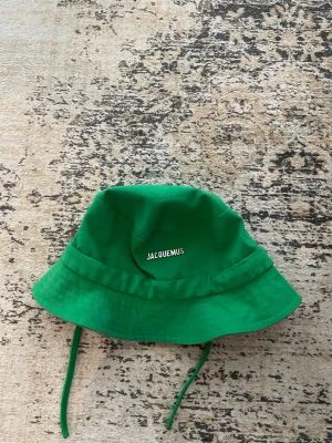 Grön bucket hat från Jacquemus - Snygg grön bucket hat från Jacquemus med logga framtill. Hatten har band så man enkelt kan ändra storlek.