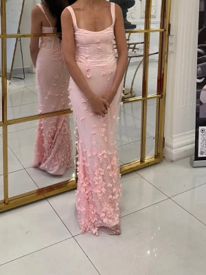 Oh polly klänning  - Klänning från Oh Polly Vasanta Embellished Fishtail Corset Gown - baby pink Säljer denna helt magiska klänning från Oh Polly. Modellen heter Vasanta Embellished Fishtail Corset Gown och har vackra 3D-blommor, parldetaljer och en supersnygg korsettrygg med snörning.  Endast använd en kväll. Ordinarie pris: €184,95.          Storlek UK 6 / US 2 vilket motsvarar EU 34 (xs) passar även om man har storlek S. (Jag är 170 cm lắng och brukar ha storlek S)