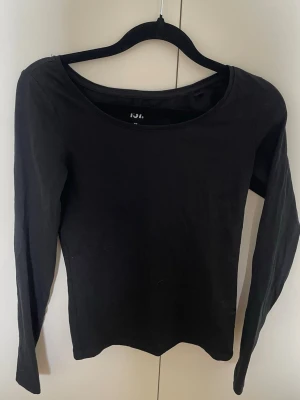 Svart långärmad topp från 157 - En enkel och stilren svart långärmad topp från 157. Tillverkad i mjuk bomull med lite stretch för skön passform. Perfekt basplagg med rund halsringning och figurnära modell.