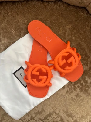 Orange sandaler exklusiva  - Snygga orange sandaler i gummi med stor 3D GG-logga framtill. Modellen har fyrkantig tå och bred rem över foten. Perfekta för dig som vill sticka ut med en färgstark och trendig look.