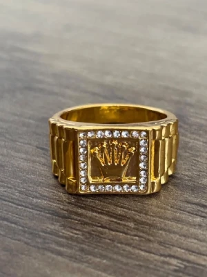 Ring med krona och kristaller  - Vår populäraste ring i guldpläterat rostfritt stål. Finns i storlekar 7,8,9, och 10. OBS går ej att få personaliserad.  Företagsinfo✨ Hör av dig till oss på Nordic Names gällande önskemål om gravyr, bild och andra personaliserade smycken. Observera att personaliserade smycken har en längre leveranstid, ca 14 dagar extra. Alla smycken levereras i en lyxig ask och med en gåva. Vi värdesätter din upplevelse som kund och skulle uppskatta din åsikt om oss som företag - lämna  gärna ett omdöme! 