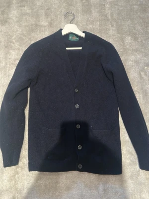Mörkblå cardigan från Alan Paine - Klassisk mörkblå cardigan från Alan Paine med v-ringning och knäppning framtill.  Strlk 48 men skulle säga att den är som en xs-s. Köpt på nk för 2099. Hör av er vid frågor eller funderingar 