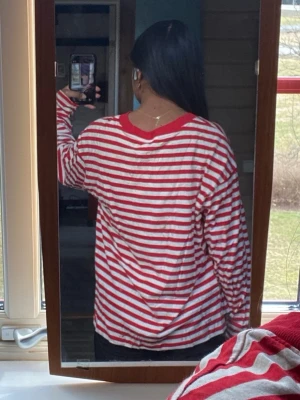 Rödvit randig långärmad topp - Säljer en oversized långärmad topp med röda och vita horisontella ränder. Tröjan har en rund halsringning och är gjord i mjuk bomull. Perfekt för en avslappnad och chill stil.