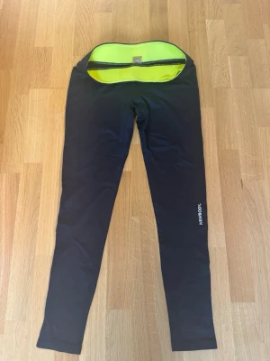 Svarta leggings från Newbody M - Säljer ett par svarta leggings från Newbody i storlek M. De har en slimmad passform och insidan är neon-gul. Materialet är 95% polyester och 5% elastan vilket gör dem stretchiga och bekväma. Perfekta för träning eller chill dagar. Använd några gånger men är i bra skick 