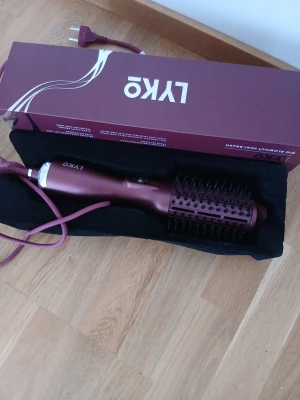 Vinröd varmluftsborste från LYKO - Elektrisk varmluftsborste från LYKO i en snygg vinröd färg. Borsten har rund form med svarta piggar och ett ergonomiskt handtag. Perfekt för att styla och torka håret samtidigt. Levereras med originalkartong och förvaringspåse.