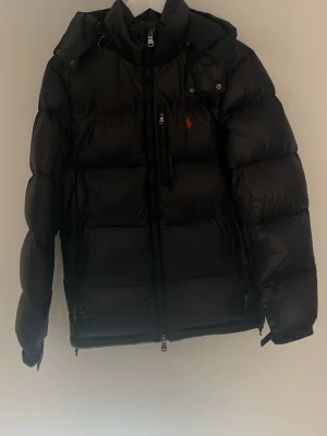 Marinblå pufferjacka från Polo Ralph Lauren - Sjukt snygg marinblå pufferjacka från Ralph lauren i toppskick, ÄKTA!! Köpt i vintras från Ralph lauren för 6099 men säljer nu för endast 2999 men kan tänka mig att gå ner i pris så tveka inte på att höra av dig! Har inte kvar kvitto men har prislappen.