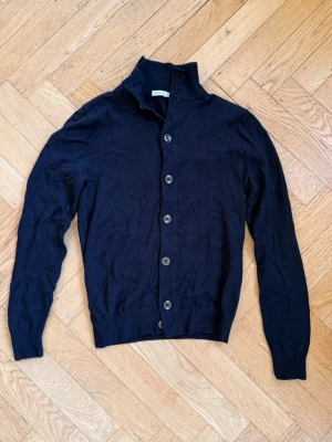 Mörkblå merinoullskofta från Suitsupply - Elegant Suitsupply-kofta i klassisk marinblått, tillverkad av högkvalitativ ull.  Detaljer:  Märke: Suitsupply Storlek: M men sitter mer år S/Xs Material: Ull Färg: Marinblå Skick: Mycket bra (sparsamt använd, utmärkt)  Funktioner:  Knappstängning Högkvalitativ ull  Kontakta mig för mer information eller foton
