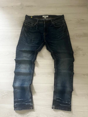 Jeans SMOG DENIM Straight Fit Distressed 👖 - Dark blue wash SMOG DENIM slim fit jeans featuring intentional distressing, whiskering, and a stylish stacked effect on the lower legs. These classic five-pocket jeans offer a modern, worn-in look perfect for casual wear.   ⭐️ Condition : 7/10 🎲 Size : 30/32 🎨 Color : Dark Blue 📦 Fast and careful shipping.