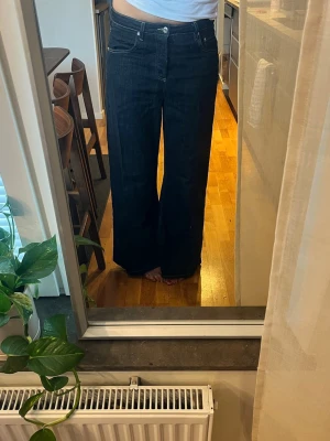 Mörkblåa vida jeans med medelhög midja - Säljer ett par mörkblå jeans med medelhög midja och vida ben