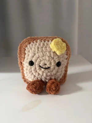 Virkad toast-mjukis med smör - Söt handvirkad jellycat toast med smörklick på!🍞 Gjord i chenillegarn med polyesterfyllning🥰 Ca 11 x 11 cm   ‼️Gosedjuret innehåller säkerhetsögon, som ej rekommenderas för barn under 3 år. 