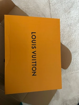 Louis Vuitton svartvita sneakers - Snygga sneakers från Louis Vuitton i svart och vitt med klassiska monogramdetaljer. Skorna har en chunky sula, vita skosnören och tydliga LV-loggor på sidan. Perfekta för dig som vill sticka ut med exklusiv streetstyle.