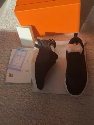 Svarta sneakers - Snygga svarta sneakers med vit och svart räfflad sula och diskreta ränder på hälen. Ovandelen är i textilmaterial och skorna har svarta snören. Perfekta för dig som vill ha en stilren och exklusiv look.