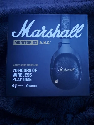Marshall Monitor III A.N.C. hörlurar - Marshall Monitor III A.N.C. är svarta over-ear hörlurar med aktiv brusreducering, Bluetooth och upp till 70 timmars trådlös speltid. De har en robust och vikbar design, Marshall-signaturljud och M-kontrollknapp. Perfekta för musik och poddar på språng.
