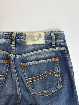 Blå jeans från Jacob Cohen - Snygga blå jeans från Jacob Cohen med klassisk femficksdesign, kontrastsömmar och läderpatch bak i midjan. Jeansen har raka ben och är tillverkade i mjuk denim med slitna detaljer för en cool look.