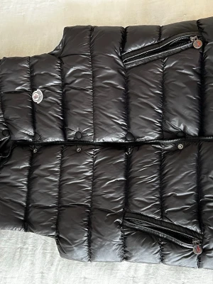 Moncler väst - Tjena säljer en svart Moncler väst.Stl 2.Tappat en knapp längst ner men inget som syns(se sista bilden).Vet ej om äkthet men den har en Scan kod inne i västen som tar dig till Moncler hemsida.Priset kan diskuteras 