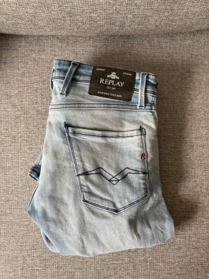 Replay Anbass ljusblå slim fit jeans - Säljer ett par ljusblå slim fit jeans från Replay, modell Anbass. Jeansen har klassisk femficksdesign, snygga sömdetaljer på bakfickan och en liten röd etikett. Tillverkade i mjuk denim med en modern tvättad look.