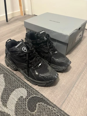 Balenciaga Track sneakers svarta - Svarta Balenciaga Track sneakers med chunky design och mesh- samt syntetpaneler. Skorna har kraftig sula, logotyp på tungan och häl, samt snörning framtill. Perfekt för dig som gillar statement-skor och streetstyle.