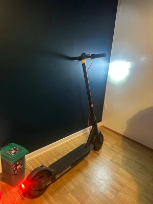 Svart elscooter med LED-display - Elektrisk scooter i svart med LED-display på styret, röd bromskabel och integrerade lampor fram och bak. Scootern har en digital hastighetsmätare och ringklocka på styret. Perfekt för smidig transport i stan.