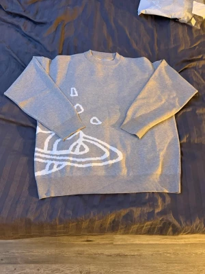 Grå stickad tröja med rymdmotiv - Säljer en grå stickad tröja med vitt rymdmotiv, där både fram- och baksidan har coola planet- och stjärndetaljer. Tröjan har rund hals, långa ärmar och ribbade muddar. Perfekt för dig som gillar unika och trendiga plagg med grafiska tryck.