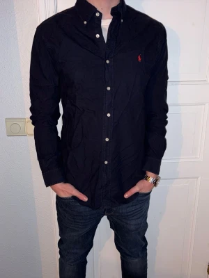 Mörkblå skjorta från Ralph Lauren - Mörkblå skjorta från Ralph Lauren i storlek M.  Fint skick till ett bra pris. Nypris: 1995kr. Mitt pris: 349kr. Vid frågor eller funderingar, tveka inte att höra av dig.