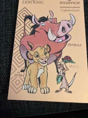  Lion King ögonskuggspalett - Ögonskuggspalett från Essence i samarbete med Lejonkungen. Paletten innehåller 14 nyanser i både matta och skimrande toner, med färger som guld, brons, beige, brunt, grönt och persika. Fyrkantiga pans med motiv från filmen och spegel i locket. Perfekt för kreativa ögonlooks.