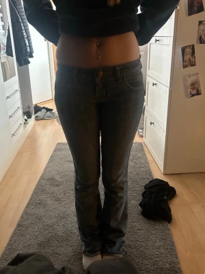 Blå bootcut jeans med låg midja, y2k - Säljer ett par blå lågmidjade jeans.   Perfekta för dig som gillar lite old style från 2000 talet. Jeansen är i storlek S men är insydda i midjan så passar även xs, går att sprätta upp. Lite slitna nere vid byxbenen men inget som syns. 💗 