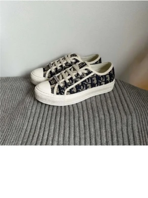 SÖKER! Dior sneakers - SÖKER!! Snygga låga sneakers från Dior med klassiskt blått och beige Oblique-mönster. Skorna har vita snören, vit sula och detaljer i canvasmaterial. Perfekta för dig som vill ha en trendig och exklusiv look.