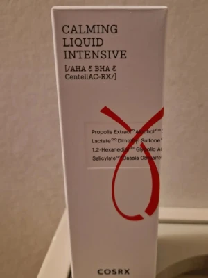 COSRX Calming Liquid Intensive toner - En toner från COSRX med AHA, BHA och CentellAC-RX som lugnar huden. Förpackningen är vit med svart text och en röd grafisk detalj. Innehåller bland annat propolisextrakt, glykolsyra och salicylsyra. Perfekt för dig som vill ha en effektiv och återfuktande toner. Obs datumet går ut 19 mars 2026