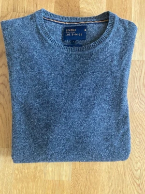 Mörkgrå ulltröja från Signal - Mysig grå stickad tröja från Signal, tillverkad av italienskt garn. Rund halsringning och ribbade muddar vid ärmslut och nederkant. Perfekt för kyliga dagar och enkel att matcha med jeans eller chinos.